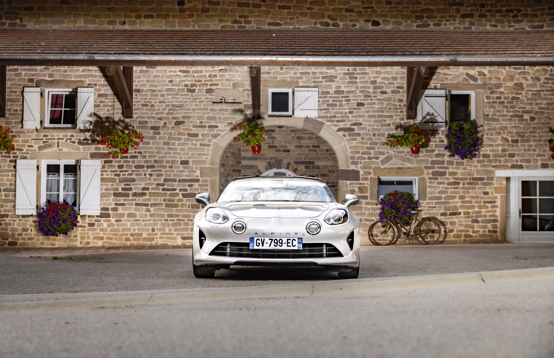 Alpine A110 GT Jean Rédelé, face avant devant une maison en pierre